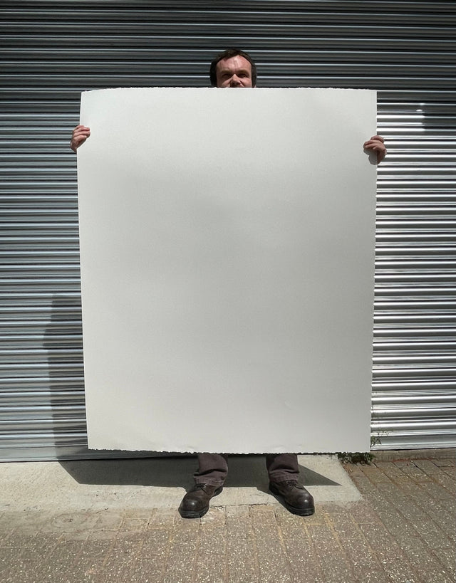 Tall artist holding a sheet of giant 400gsm watercolour drawing paper to demonstrate scale